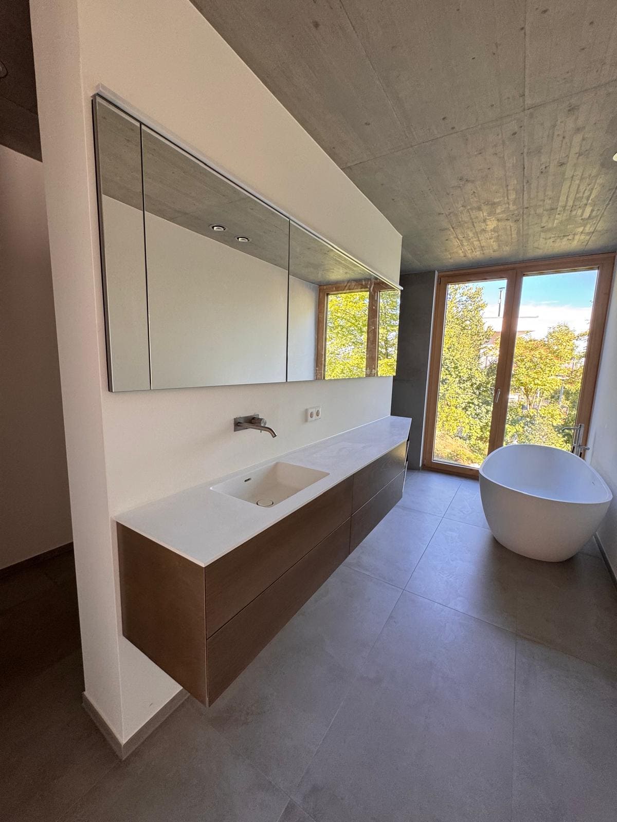 Moderne Badezimmer mit schwebendem Waschtisch und Spiegelschrank, mit freistehender Badewanne